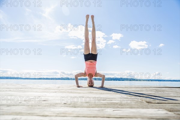 Caucasian woman practicing yoga on wooden dock