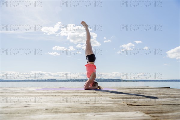 Caucasian woman practicing yoga on wooden dock