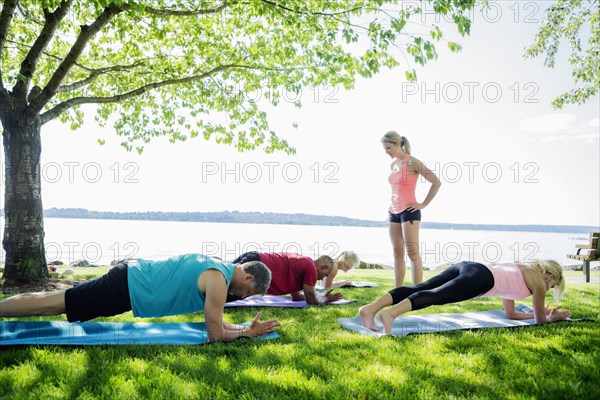 Caucasian people practicing yoga outdoors