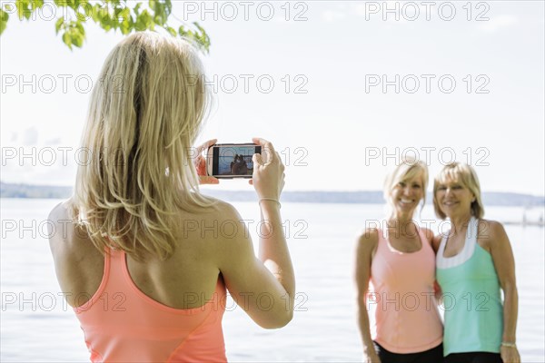 Caucasian woman photographing women outdoors