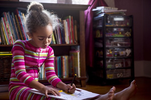 Mixed race girl drawing in living room