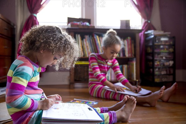 Mixed race girls drawing in living room