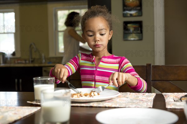 Mixed race girl eating at table