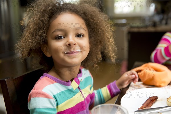 Mixed race girl with milk mustache at table