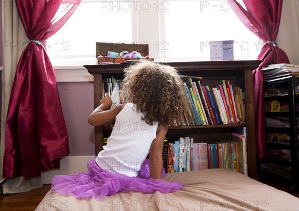 Mixed race girl picking books from shelf