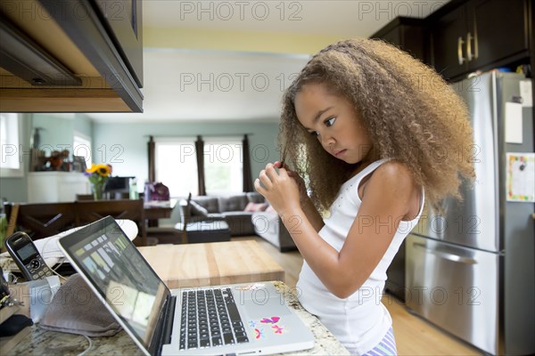 Mixed race girl using laptop in kitchen