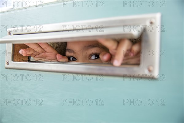 Mixed race girl peeking through mail slot