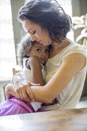 Mother holding daughter at table