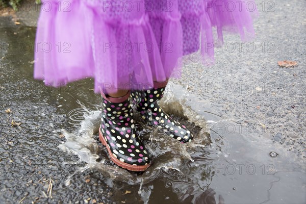 Mixed race girl playing in puddle