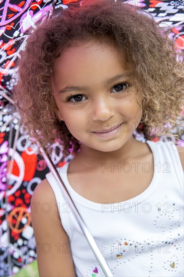 Mixed race girl smiling under umbrella