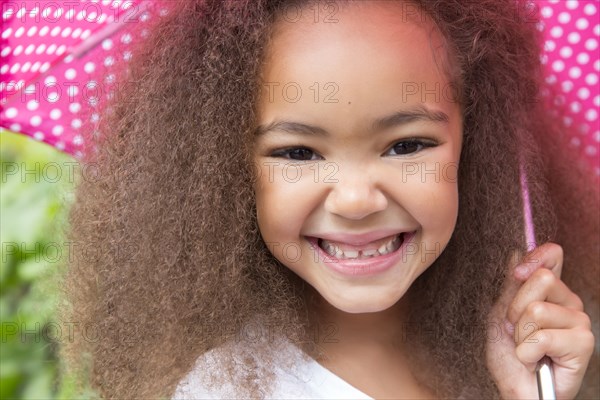 Mixed race girl smiling under umbrella