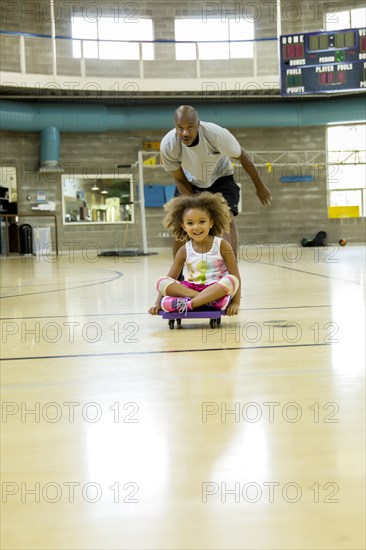 Father and daughter playing on basketball court