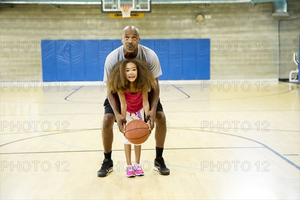 Father and daughter playing on basketball court