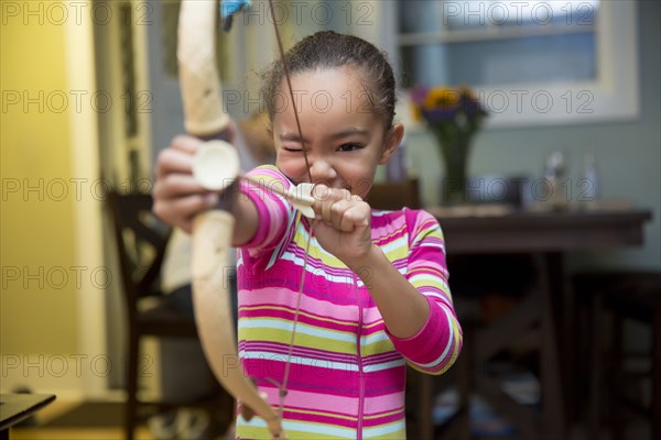 Mixed race girl playing with bow and arrow