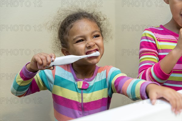 Mixed race girls brushing their teeth