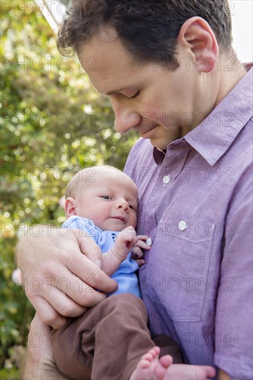 Father holding newborn son outdoors