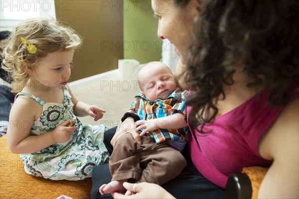 Caucasian girl watching mother hold newborn boy