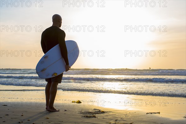 Mixed race man holding surfboard on beach