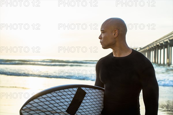 Mixed race man holding surfboard on beach