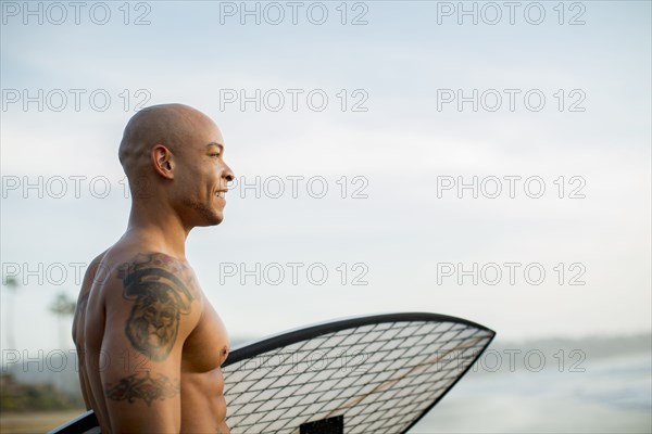 Mixed race man holding surfboard on beach