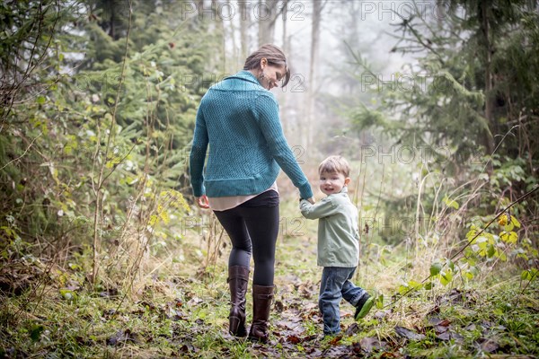 Caucasian mother and son walking in forest