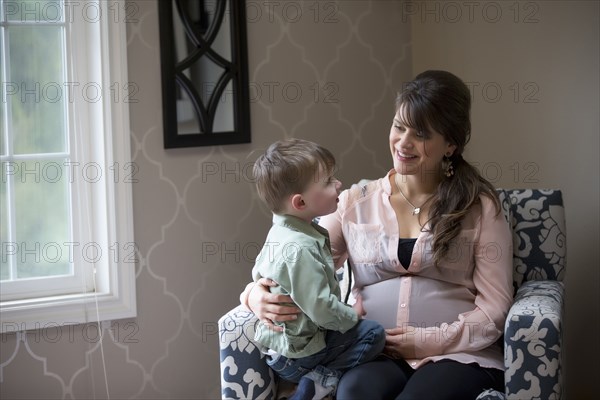 Pregnant Caucasian mother sitting with son