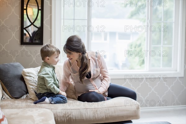 Pregnant Caucasian mother sitting with son in living room