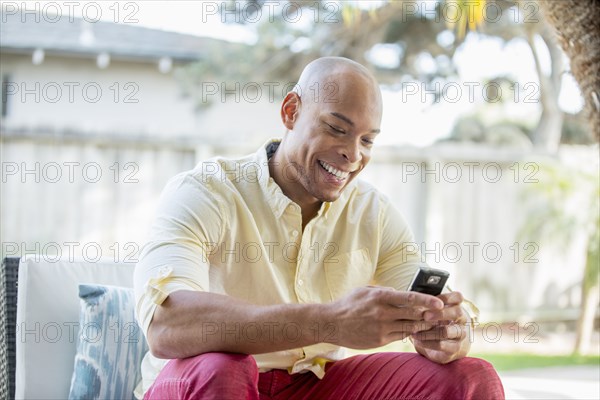 Mixed race man using cell phone in backyard