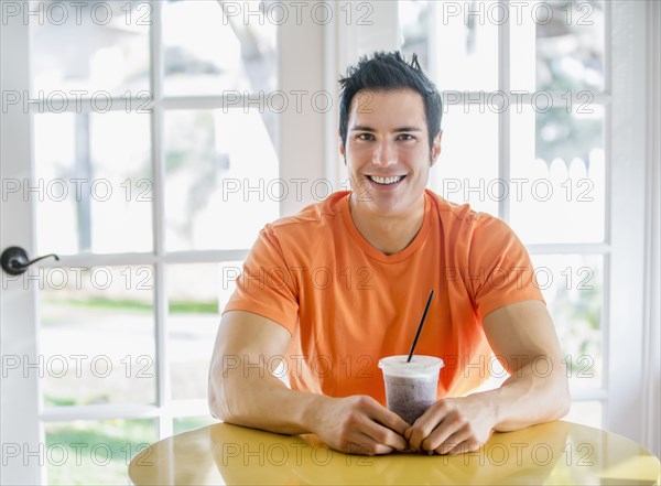 Caucasian man drinking smoothie in kitchen