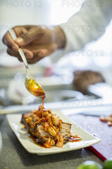 Black chef making pork belly and kimchee in restaurant