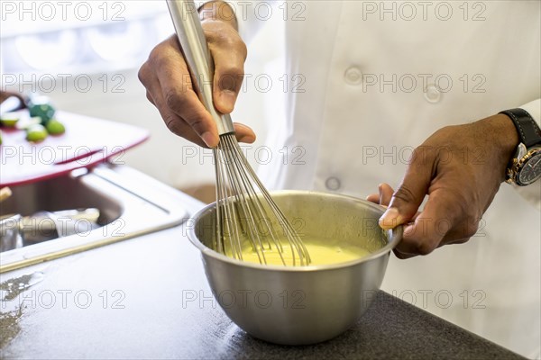 Black chef whisking eggs in restaurant