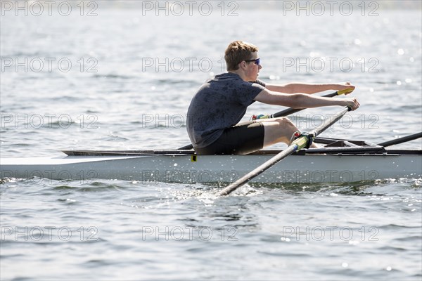 Caucasian teenage boy rowing on river