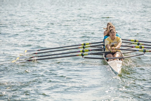 Teenagers rowing together on lake