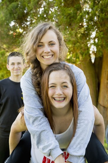 Caucasian teenage girls piggybacking outdoors