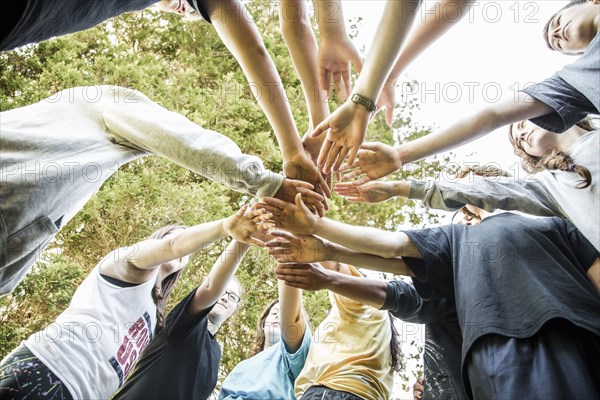 Caucasian teenagers putting hands together in huddle