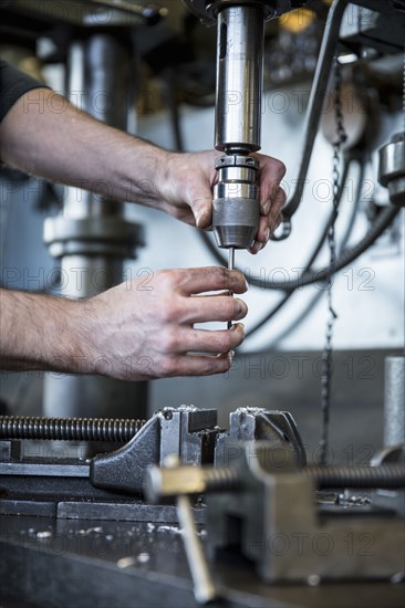 Caucasian man operating drill machinery in metal shop