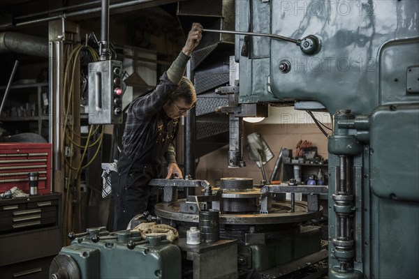 Caucasian man using machinery in metal shop