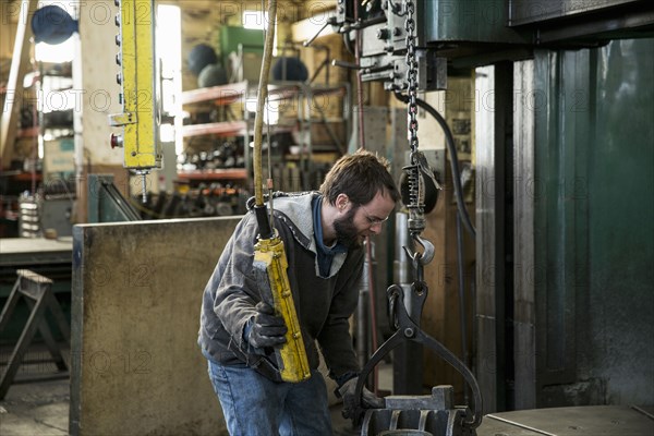 Caucasian man using machinery in metal shop