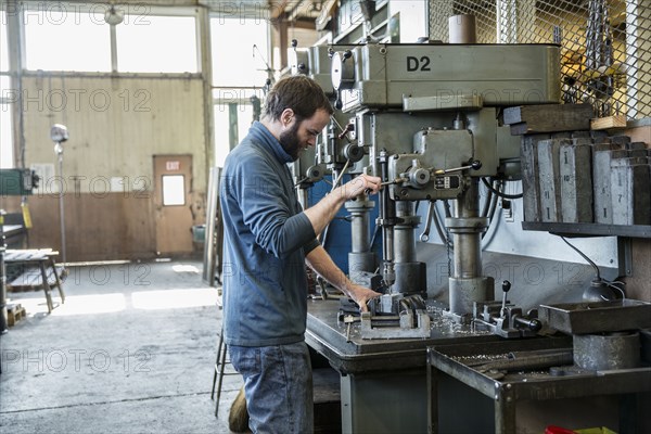 Caucasian man using drilling machine in metal shop