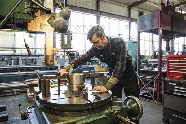 Caucasian man using machinery in metal shop