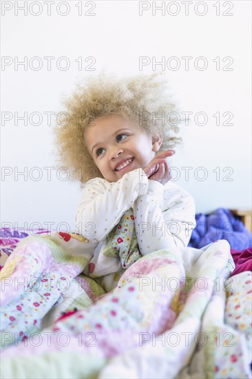 Mixed race girl smiling in bed