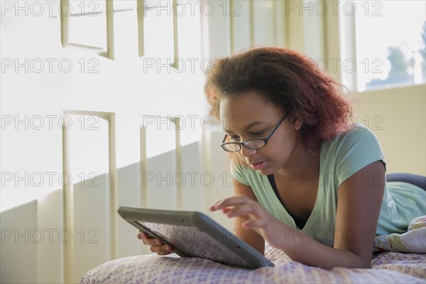 Mixed race girl using digital tablet in bed