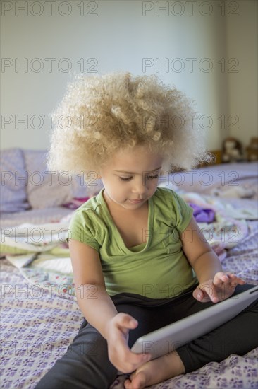 Mixed race girl using digital tablet in bed