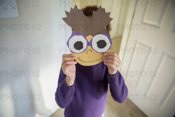 Mixed race girl holding mask over face