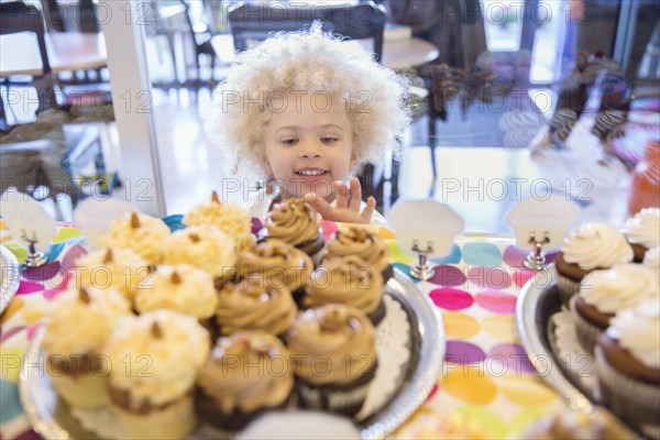 Mixed race girl picking cupcakes in bakery