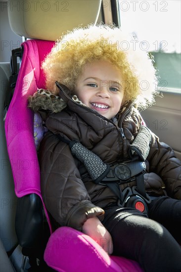 Mixed race girl smiling in back seat of car