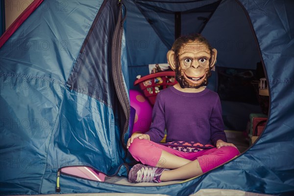 Mixed race girl wearing mask in tent