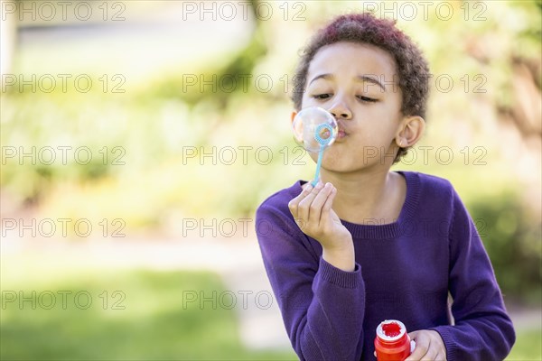 Mixed race girl blowing bubbles outdoors