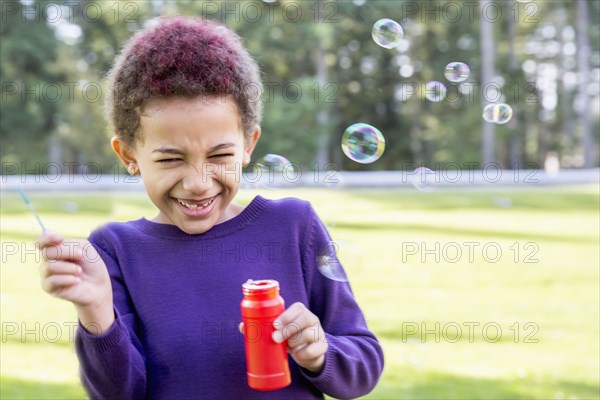 Mixed race girl blowing bubbles outdoors