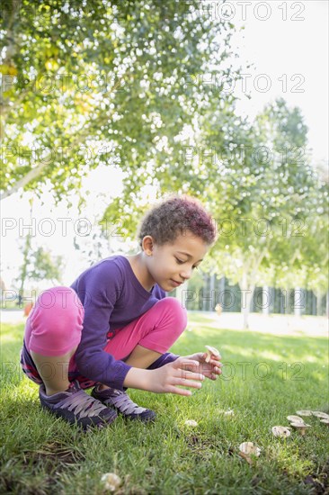 Mixed race girl examining mushrooms outdoors